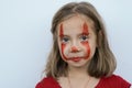 Portrait of a little girl smeared with red paint face