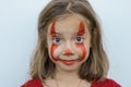 Portrait of a little girl smeared with red paint face