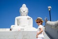 Portrait of little girl standing near Big Buddha statue in Phuket, Thailand. Concept of tourism in Asia and famous