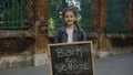 Portrait of little girl standing turn around smilling and holding schoolboard with text back to school on the street