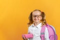 Portrait of a little girl students in glasses with a backpack and lunchbox on a yellow background. Back to school. Royalty Free Stock Photo