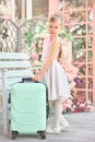 Portrait of a little girl with a suitcase. a child with a hat travels alone