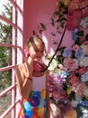 Portrait of a little girl in a sarafan with a handset in her hand, which stands in a telephone booth decorated with flowers Royalty Free Stock Photo