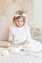 Portrait of a little girl Toddler with a headband on her head in the form of deer horns and a Christmas toy in her hands. Royalty Free Stock Photo