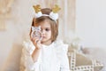 Portrait of a little girl Toddler with a headband on her head in the form of deer horns and a Christmas toy in her hands. Royalty Free Stock Photo