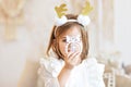 Portrait of a little girl Toddler with a headband on her head in the form of deer horns and a Christmas toy in her hands. Royalty Free Stock Photo