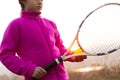 Portrait of little girl is training skill, outside of tennis court, in field at sunset. Wearing pink sweater. Royalty Free Stock Photo