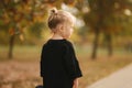 Portrait of little girl walking in the part in autumn. Blond hairl female kid outside. Warm autumn. Back view of kid