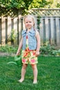 Little girl watering green plants on backyard