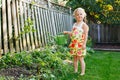 Little girl watering green plants on backyard