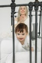 Portrait of a little girl who, having woken up, plays in bed with her mother, crawls away from her and smiles Royalty Free Stock Photo