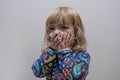 Portrait of a little girl who painted her face with children`s markers, laughing and covering her face with her hands. Royalty Free Stock Photo