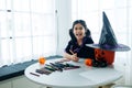 Portrait of little girl in witch costume painting halloween pumpkin on table at home Royalty Free Stock Photo