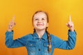Portrait of a little girl on a yellow background. Child shows two index finger upward. Copy space Royalty Free Stock Photo