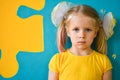 Portrait of a little girl in yellow dress on a yellow and blue background with a puzzle Royalty Free Stock Photo