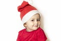 Little happy girl in festive clothes, santa claus hat in white. Cute child in Christmas clothes is waiting for the holiday. Royalty Free Stock Photo