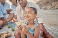 Portrait of a little hispanic girl having a snack while on a picnic with her family at the beach. Mixed race girl having Royalty Free Stock Photo