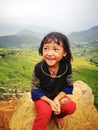Portrait of a little Hmong (Miao) minority girl sitting on a rock