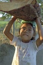 Portrait little Latino girl carrying firewood on head