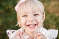 Portrait of a little laughing beautiful girl on nature on summer day vacation. child in dress is playing in the green Royalty Free Stock Photo