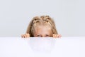 Portrait of little preschool girl, child playing hide-and-seek game isolated over white studio background.