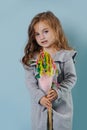 Portrait of a little girl riding on a hobbyhorse over blue background