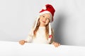 Portrait of little pretty girl laughs in Santa hat with sale advertising empty blank. Holding Xmas cardboard on white background