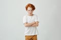 Portrait of little red haired boy with cute freckles in white tshirt looking in camera with offended expression when his Royalty Free Stock Photo