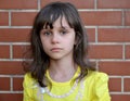 Portrait of the little sad girl against the background of a brick wall Royalty Free Stock Photo