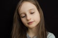 Portrait of a little sad girl with long blond hair and closed eyes on black background in studio Royalty Free Stock Photo