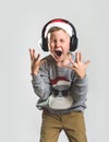 Portrait of a little Santa Clause boy in headphones. Emotional singing loudly while listening to music. Child shout
