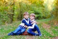 Portrait of little school kids boys sitting in forest. Happy children, best friends and siblings having fun on warm Royalty Free Stock Photo