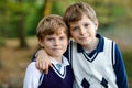 Portrait of little school kids boys sitting in forest. Happy children, best friends and siblings having fun on warm Royalty Free Stock Photo