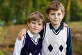 Portrait of little school kids boys sitting in forest. Happy children, best friends and siblings having fun on warm Royalty Free Stock Photo