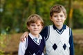 Portrait of little school kids boys sitting in forest. Happy children, best friends and siblings having fun on warm Royalty Free Stock Photo