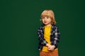 Portrait of little shy boy, child in yellow T-shirt and checkered shirt posing over green studio background. Concept of Royalty Free Stock Photo