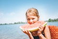 Portrait of Little smiling Girl eating red watermelon portrait on the river beach Royalty Free Stock Photo