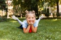 Portrait of a little smiling girl lying on the grass. schoolgirl lies on the grass in the park Royalty Free Stock Photo