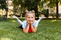 Portrait of a little smiling girl lying on the grass. schoolgirl lies on the grass in the park Royalty Free Stock Photo