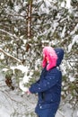 Portrait of little smiling happy girl in pink warm fur hood walking outside on nature winter snowy forest background Royalty Free Stock Photo