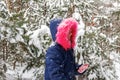 Portrait of little smiling happy girl in pink warm fur hood walking outside on nature winter snowy forest background Royalty Free Stock Photo