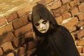 Portrait of a little teenager girl in a zombie costum against a brick wall. Halloween and day of the dead concept. Zombie looks at Royalty Free Stock Photo