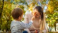 Portrait of little toddler boy and his mother playing with fallen yellow leaves at autumn park Royalty Free Stock Photo