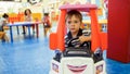 Portrait of little toddler boy riding in toy shopping cart for children in shopping mall Royalty Free Stock Photo