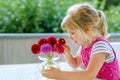 Portrait of little toddler girl admiring bouquet of blooming red and pink dahlia flowers. Cute happy child smelling and Royalty Free Stock Photo