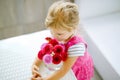 Portrait of little toddler girl admiring bouquet of blooming red and pink dahlia flowers. Cute happy child smelling and Royalty Free Stock Photo