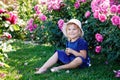 Portrait of little toddler girl in blossoming rose garden. Cute beautiful lovely child having fun with roses and flowers Royalty Free Stock Photo