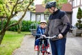 Portrait of little toddler girl with security helmet on the head sitting in bike seat and her father with bicycle. Safe Royalty Free Stock Photo