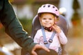 Portrait of little toddler girl with security helmet on the head sitting in bike seat and her father or mother with Royalty Free Stock Photo