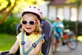 Portrait of little toddler girl with security helmet on the head sitting in bike seat of parents. Boy on bicycle on Royalty Free Stock Photo